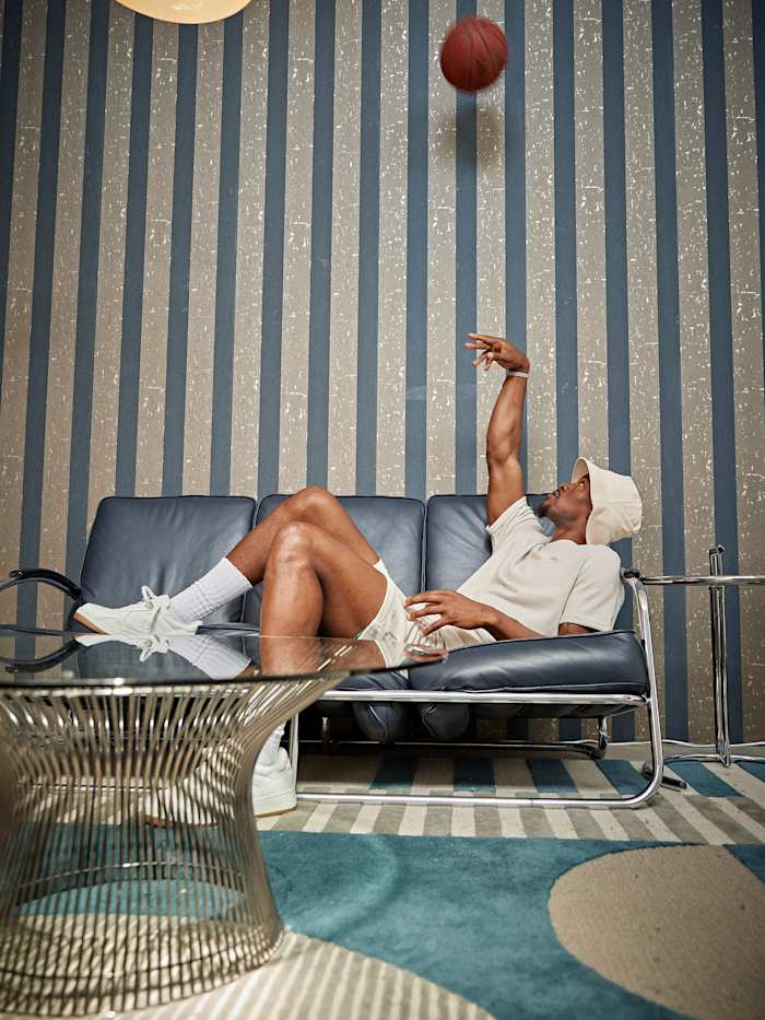 Jimmy Butler tosses a ball up in the air while laying on a couch during a photo shoot.
